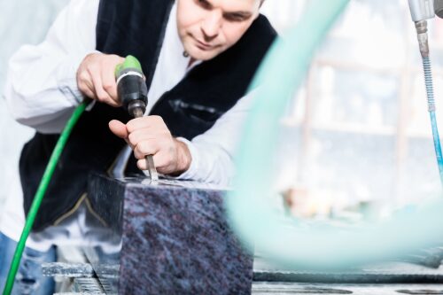 Stonemason working with pneumatic chisel